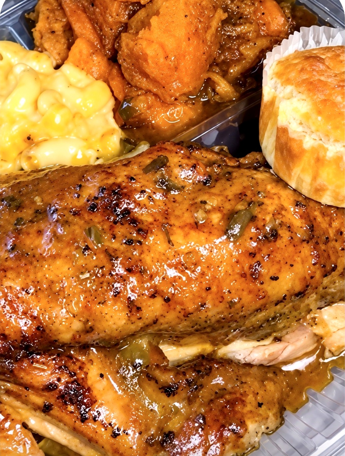 Baked chicken with mac and cheese, candied yams, and cornbread in a to-go container