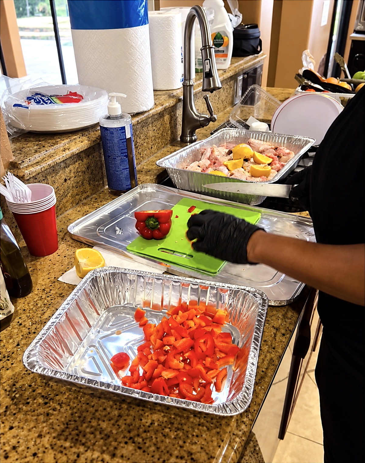 Chef Candy slicing fresh red bell peppers while preparing a private menu